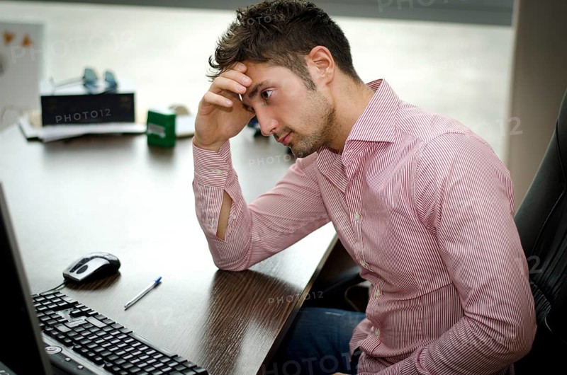 Preoccupied, worried young male worker staring at computer screen in his office