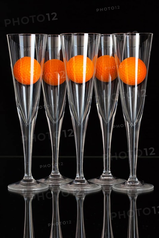 Five glasses of champagne and orange golf balls on the glass plate