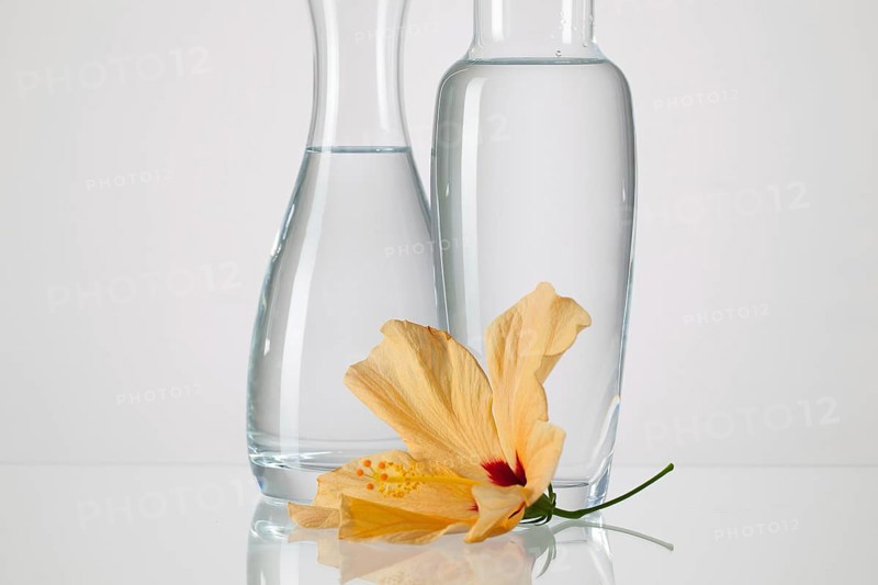 Two vases with clean water and hibiskus flower on a glass table