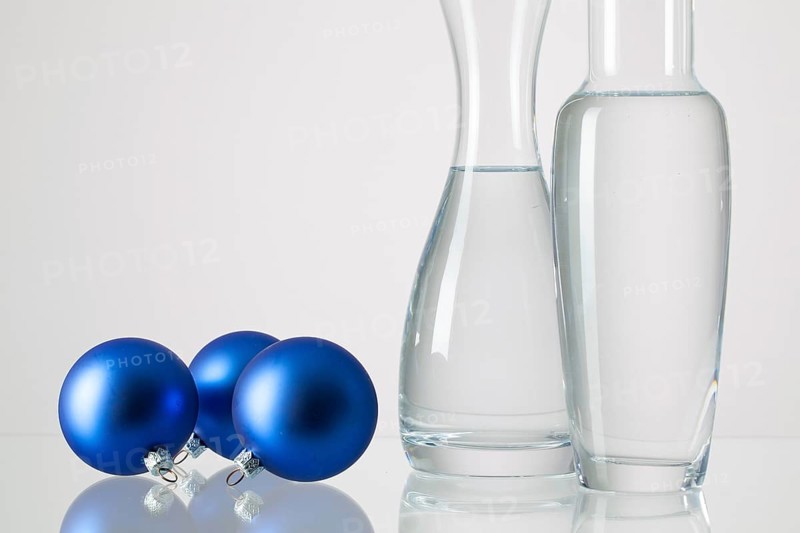 Two vases with clean water and Christmas decoration on a glass table