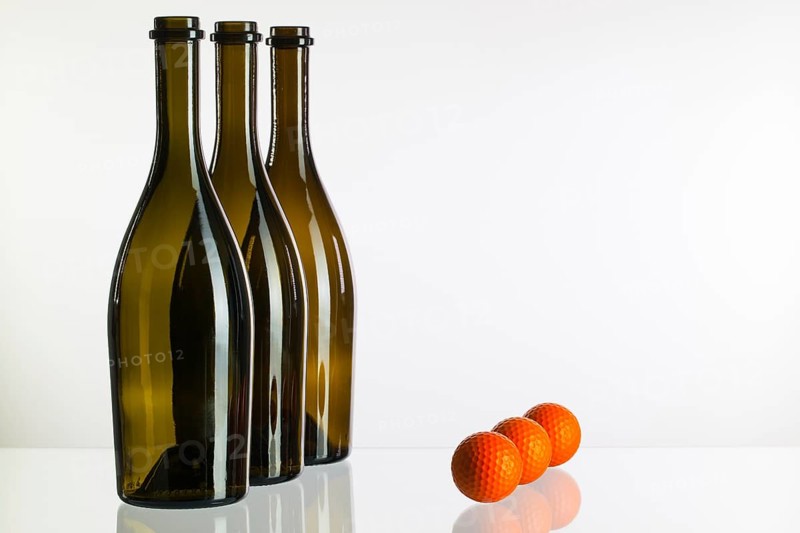 Empty three wine bottles and golf balls on a glass desk