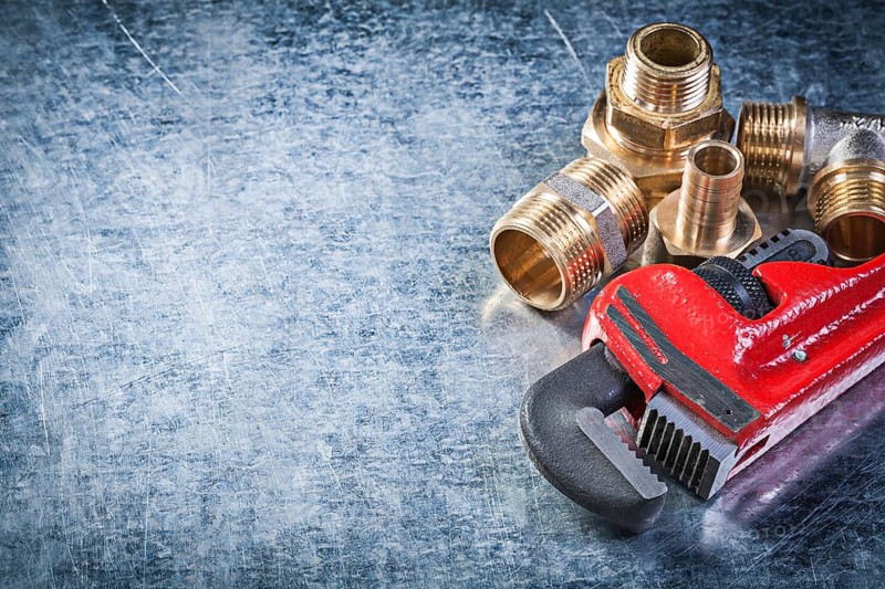 Monkey wrench brass nipple hose connectors on metallic background plumbing concept