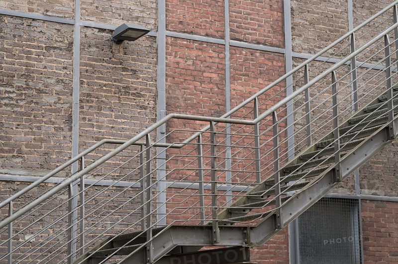 Metal fire escape climbing a brick wall with a lamp