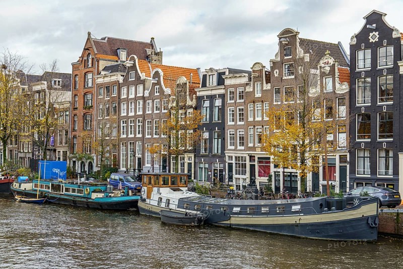 Row of stately buildings along the canal as autumn colours the trees, Amsterdam, Netherlands