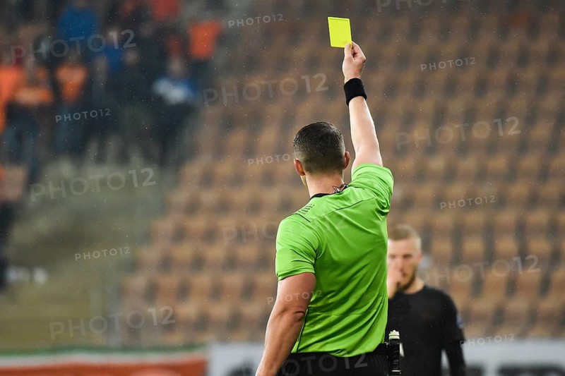 Referee shows footballer yellow card during soccer match at the stadium