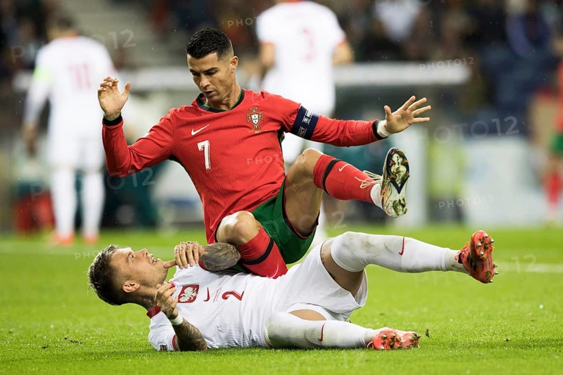 Football match, captain Cristiano RONALDO CR7 Portugal on the stomach of Kamil PIATKOWSKI Poland kneeling with his left leg and falling backwards with his right leg raised, hands outstretched upwards, looking at his opponent, Kamil PIATKOWSKI Poland lying on the ground on the grass screaming with his left leg up and direct eye contact with Cristiano RONALDO Portugal, Estadio do Dragao, Porto, Portugal, Europe