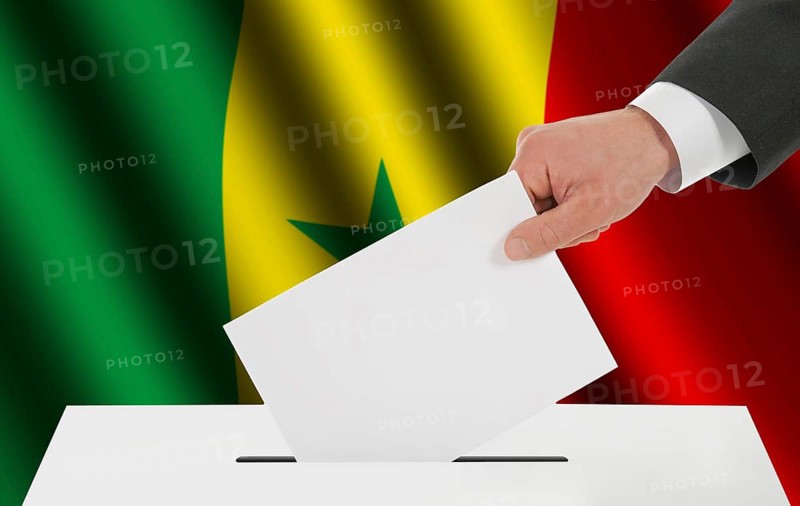 The Senegal flag and the hand with the bulletin about the ballot box