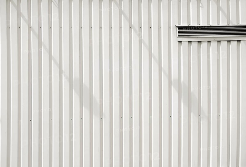 A modern façade of a shopping centre and DIY store made of checker plate with a ventilation slot and shade