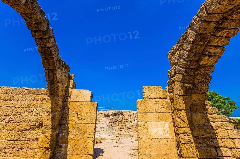 Ruins of ancient Caesarea against the background of the blue southern sky. Excursion to the Archaeological Park of the Roman Empire. The concept of phototourism