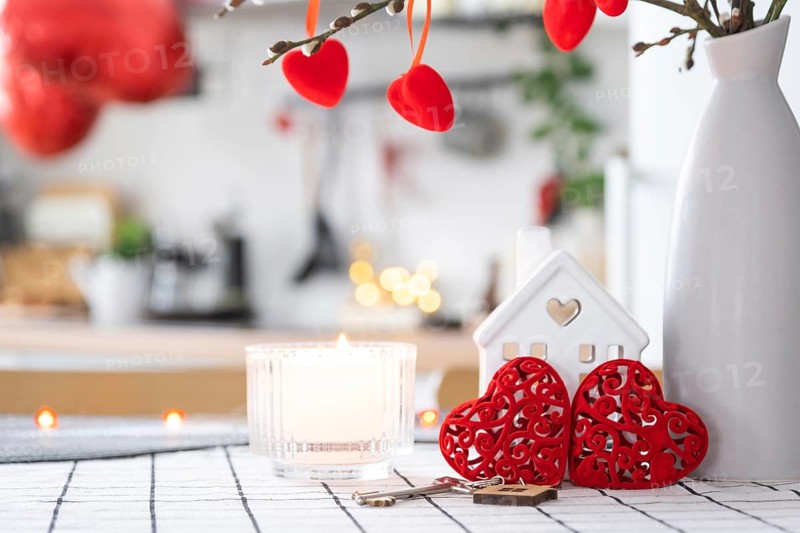Key to house of cozy home with Valentine decor on table of kitchen. Gift for valentines day, family love nest. Building, design, project, moving to new house, mortgage, rent and purchase real estate