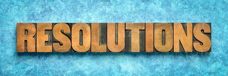 Resolutions word abstract in vintage letterpress wood type blocks against blue textured bark paper, goal setting concept