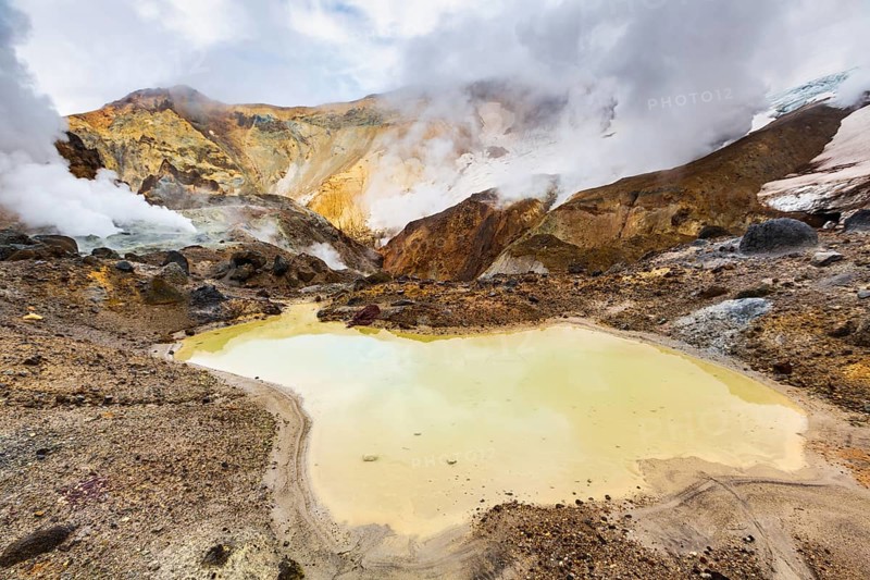 Lake in crater of active volcano. Beautiful dramatic volcanic landscape: hot spring, fumarole, geothermal gas-steam activity. Popular travel destinations for hike, active vacation, mountain climbing