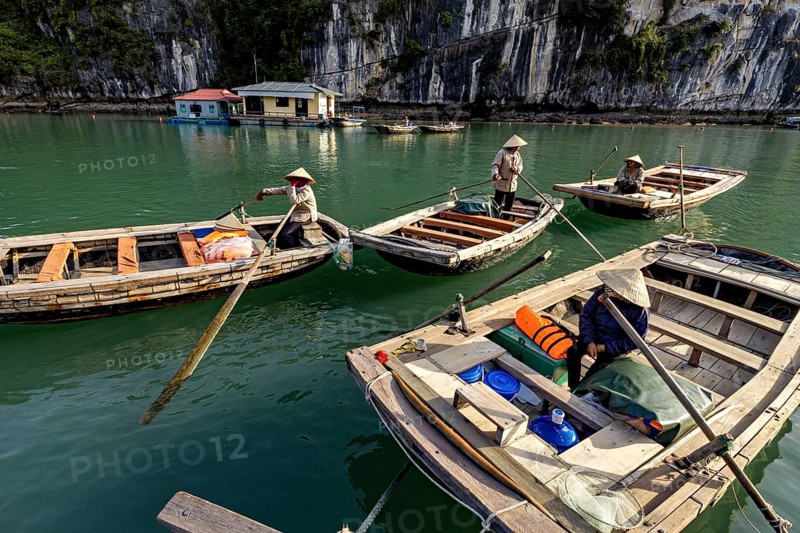 Boats with people in front of a rock, during a calm river trip, rowing boats for tourists in Halong Bay in Vietnam