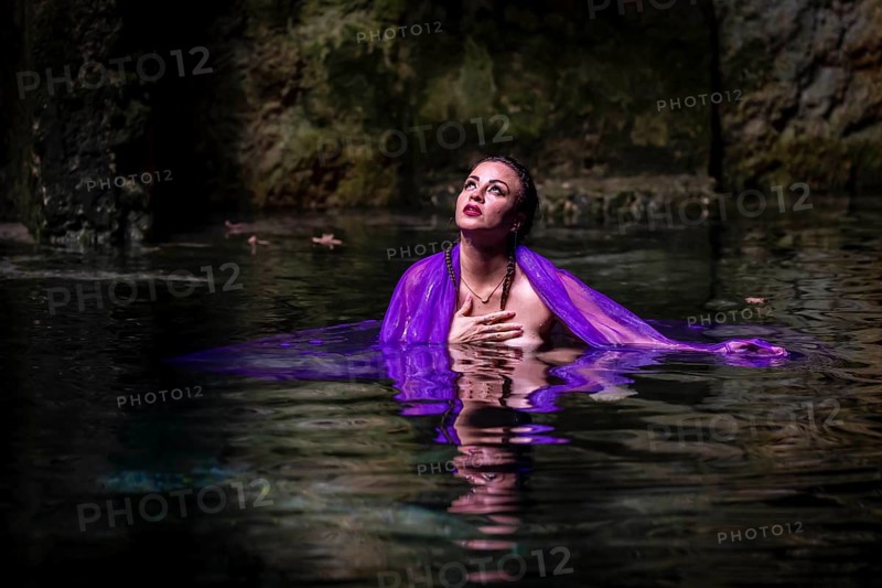 A beautiful nude latin model enjoys the gorgeous water in a colorful cenotes in Yucatan Merida, Cuzama, Mexico, Central America