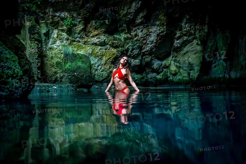 In Cuzama, Yucatan, Mexico, a stunning model revels in the vibrant hues of a cenote's blue and green waters, creating a picturesque scene of natural beauty, Cuzama, Mexico, Central America