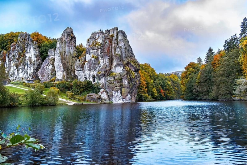 The 40 metre high Externsteine form a striking natural monument in a tranquil nature reserve in Germany. Surrounded by autumnal colours, the reflections of the rocks and foliage create a picturesque scene on the lake