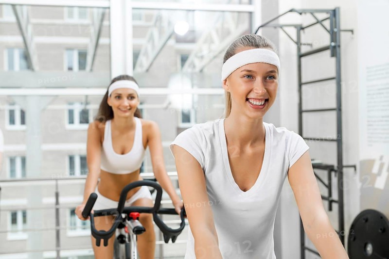 Small group of young people exercising on bikes in fitness center