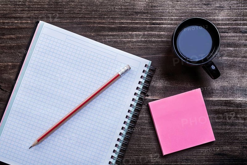 Open notepad pencil reminder note and cup of coffee on wooden board office concept