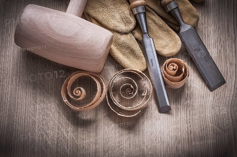 Wooden mallet curled up shavings firmer chisels leather gloves on wood board construction concept