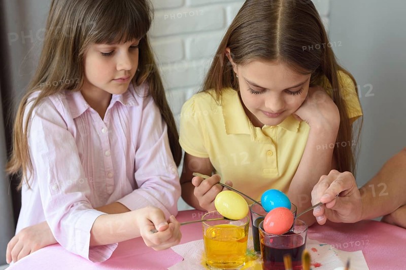 Children stain eggs in a special dye in glasses