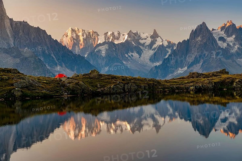 Beautiful morning by the lake with a red tent on the shore