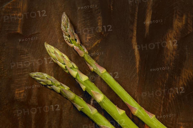 Three asparagus over dark brown wooden background