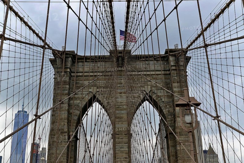 Brooklyn Bridge in Brooklyn, Manhattan, New York, USA United States of America, Symmetrical view of the Brooklyn Bridge with skyscrapers and flag in the background, New York City, USA, North America