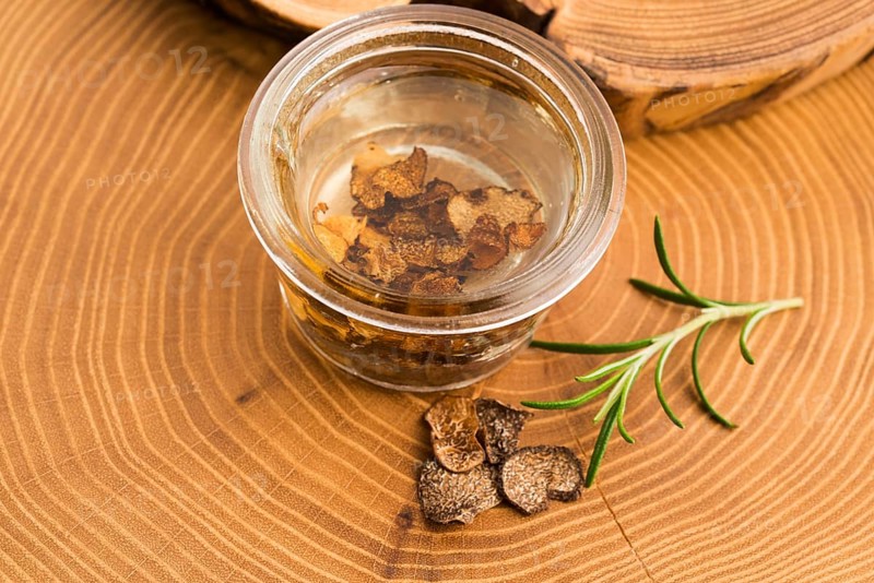 Sliced black truffle in olive oil in small jar and fresh rosemary
