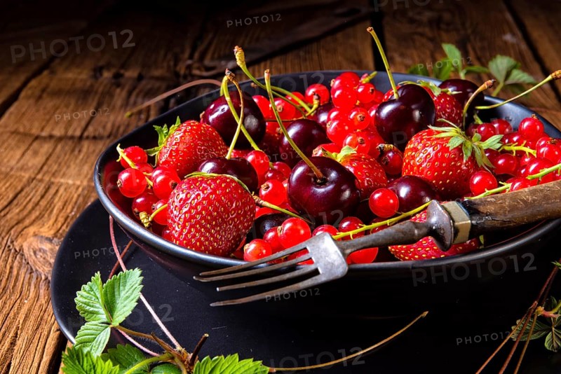 Bowl with different fruits such as strawberry, red currant, and cherry