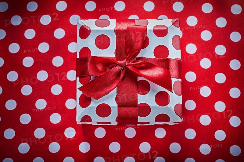 White present box with tied ribbon on polka-dot red fabric celebrations concept