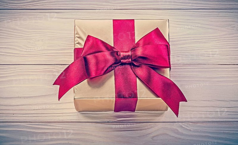Wrapped present box on wooden board directly above holidays concept