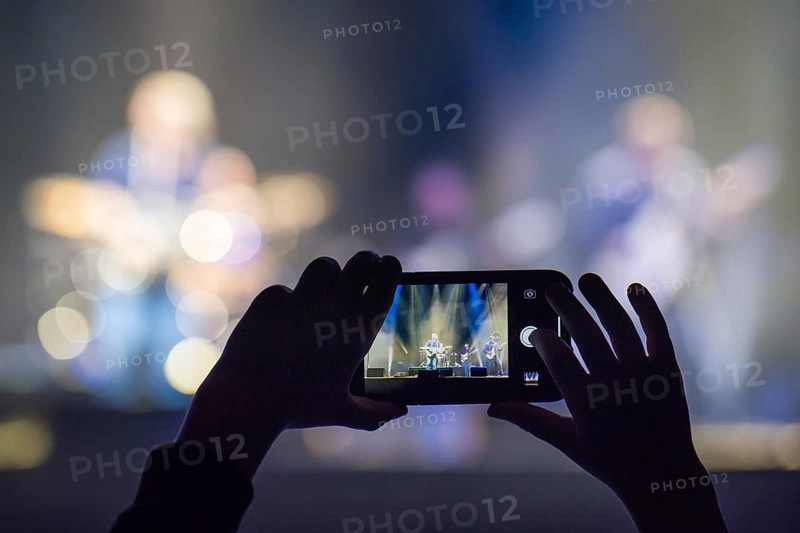 Fan holding smartphone and recording or taking picture during a concert
