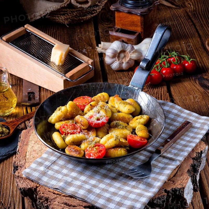 Gnocchi baked with green pesto, cherry tomatoes and parmesan