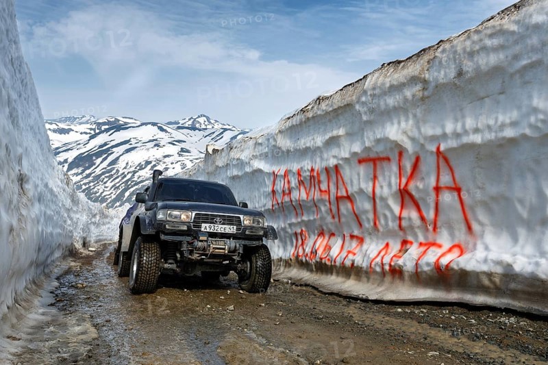 KAMCHATKA PENINSULA, RUSSIAN FAR EAST, JUNE 18, 2017: Japanese extreme off-road expedition car Toyota Land Cruiser driving on mountain road in snow tunnel surrounded by high snowdrifts