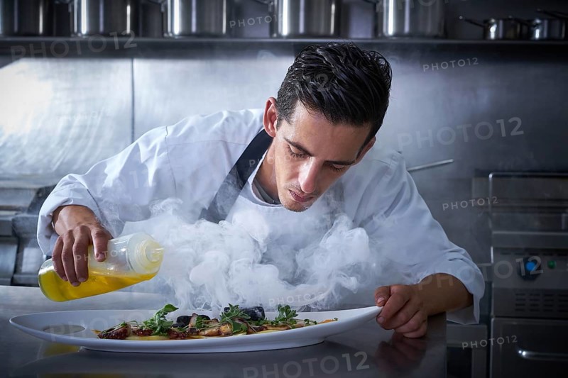 Chef working in kitchen with smoke and oil at restaurant
