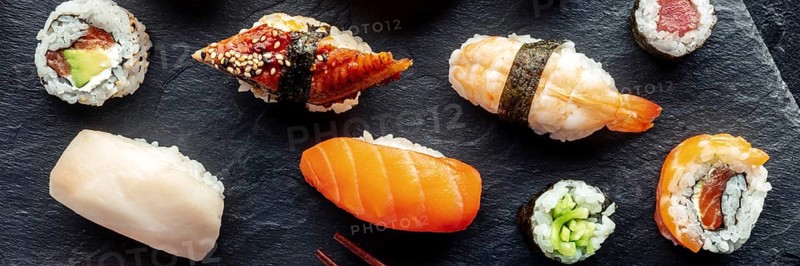 Sushi overhead flat lay panorama. Rolls, maki, nigiri on a black background, Japanese food. Salmon, eel, shrimp and other seafood with rice on a plate at an Asian restaurant, Food photography, Food photography