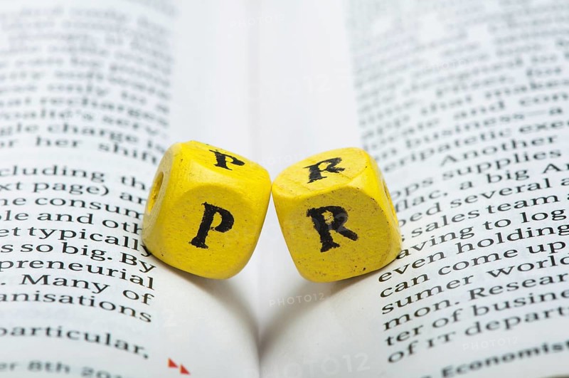 Word PR.Wooden cubes on newspaper. Close up studio shot