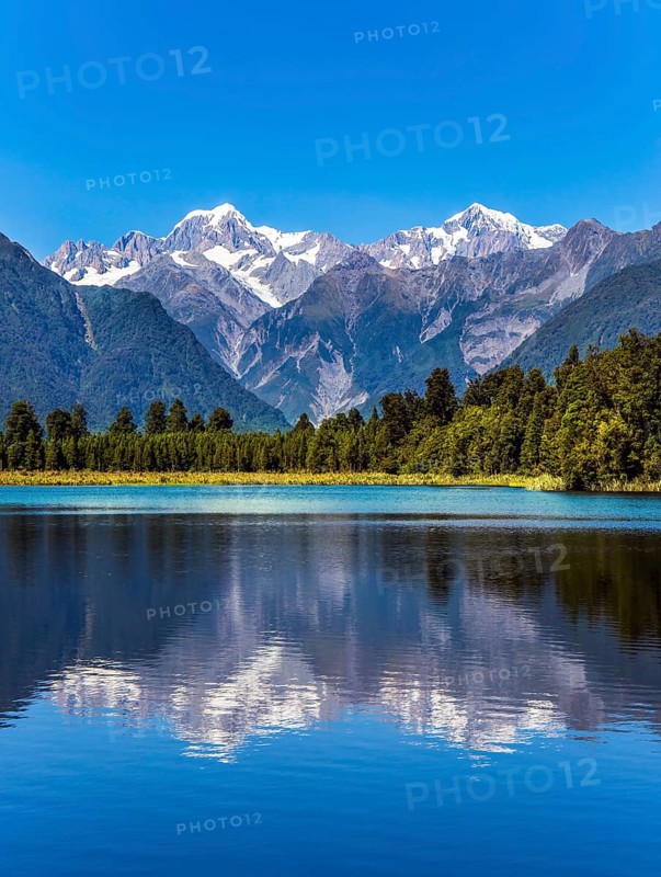 The forests and Mount Cook and Mount Tasman. Magnificent snow-capped mountains surround the smooth, cold waters of Lake Matheson.The concept of ecological, active and photo tourism