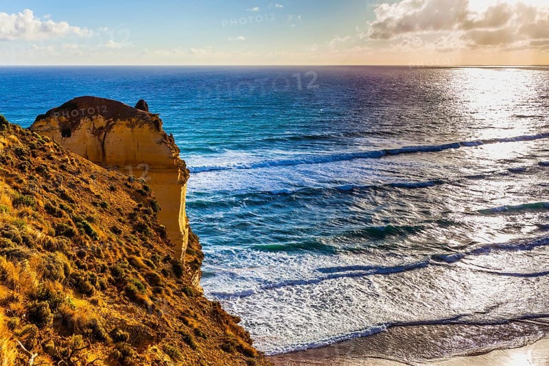 Powerful ocean surf at sunset. The Great Ocean Road. Steep and rocky ocean shore of Australia. The concept of exotic, active and photo-tourism