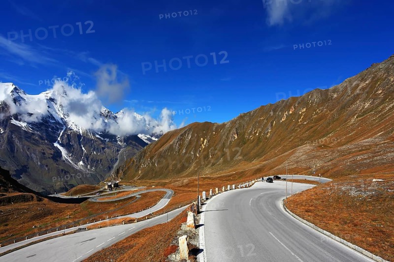 Austrian Alps. Tape highway winds between hillsides yellowed. Excursion to the picturesque panoramic way Grossgloknershtrasse. Sunny day in early autumn