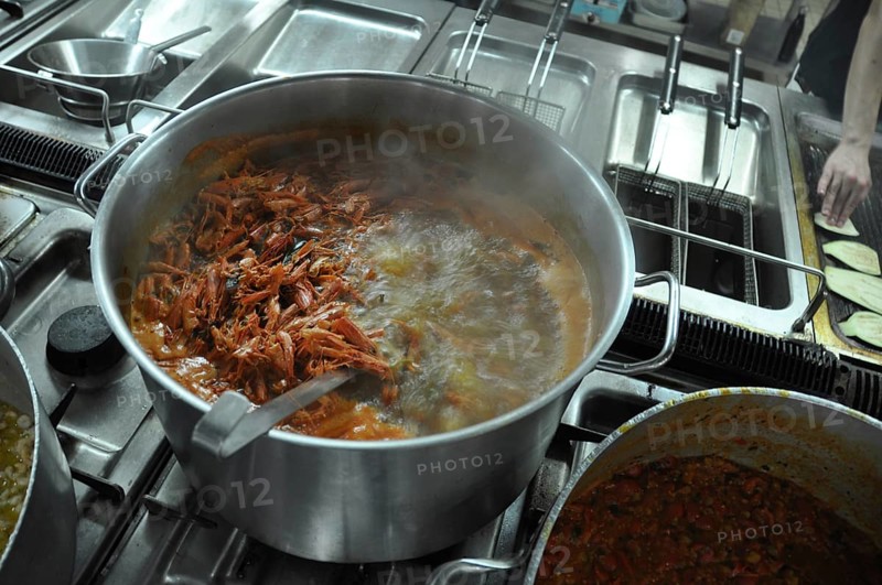 Shrimp boiling in a large pot on a stove in a busy kitchen setting, Cooks and chefs prepare dinner with the typical Mediterranean Diet at a luxury resort in Sciacca, Sicily