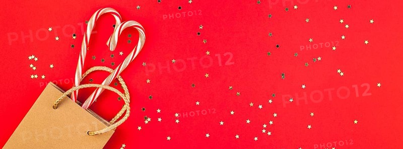 New Year or Christmas decoration flat lay top view Xmas holiday celebration shopping concept decor sweets golden stars glitter on red paper background. Template frame long wide banner