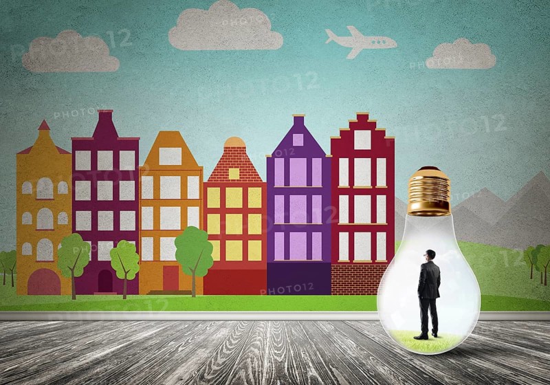 Businessman inside light bulb against city drawn concept