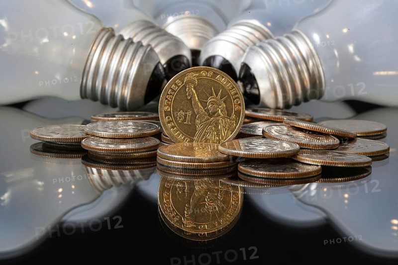 Wasteful bulbs and U.S. dollar coins on a black table
