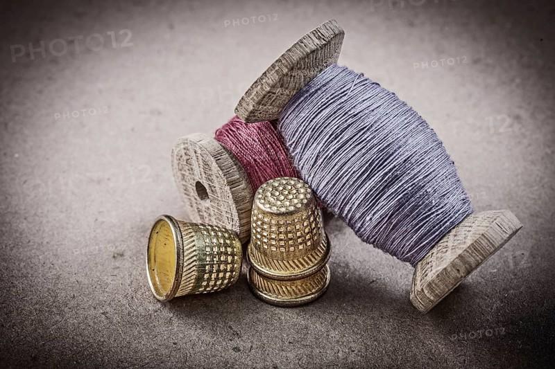 Spools of sewing threads thimbles on vintage background needlework concept