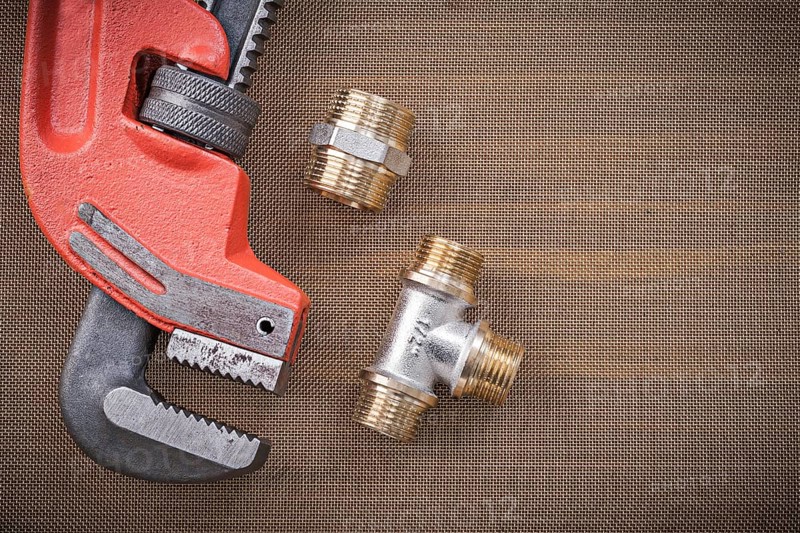Pipe wrench brass plumbing fixtures on cleaning mesh filter grid