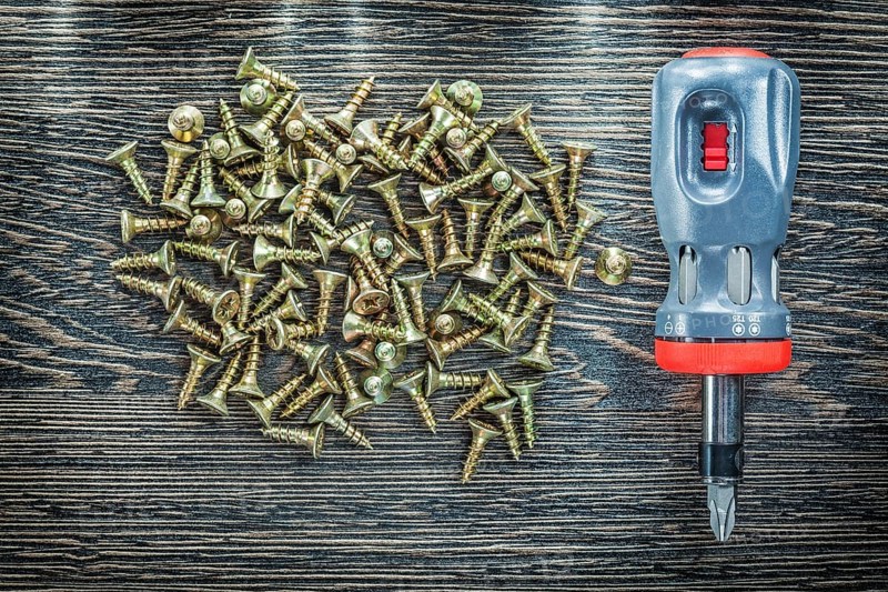 Screwdriver tapping screws on wooden board