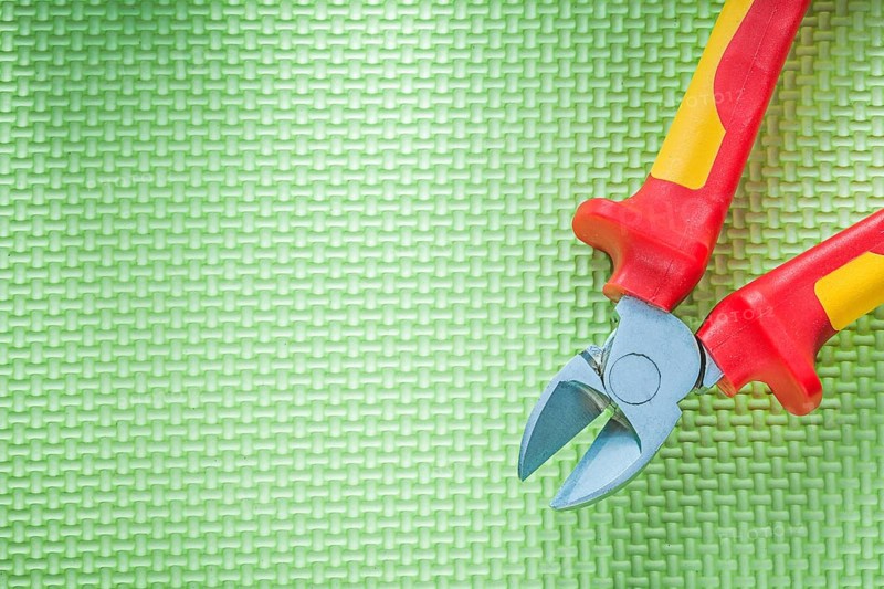 Sharp insulation nippers on green background electricity concept
