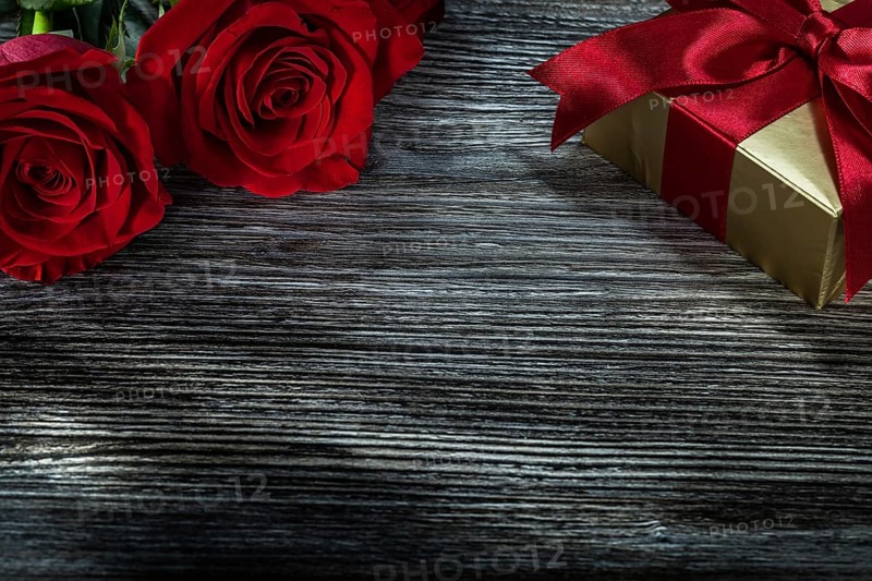 Golden gift box red roses on wooden board