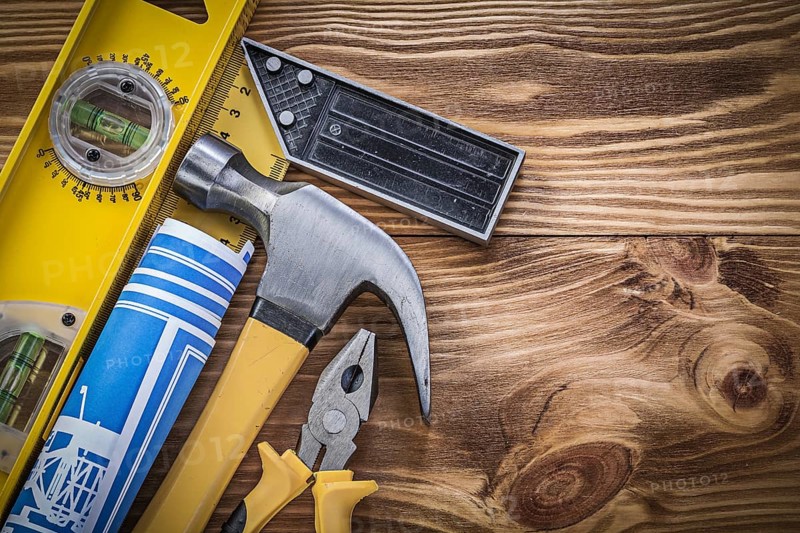 Blue blueprints construction level square ruler claw hammer pliers on wooden board